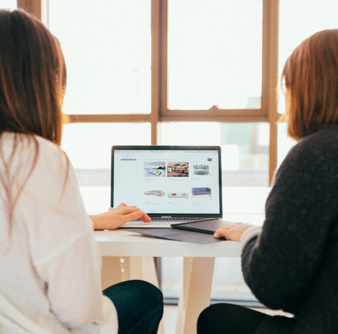two women talking while looking at laptop computer